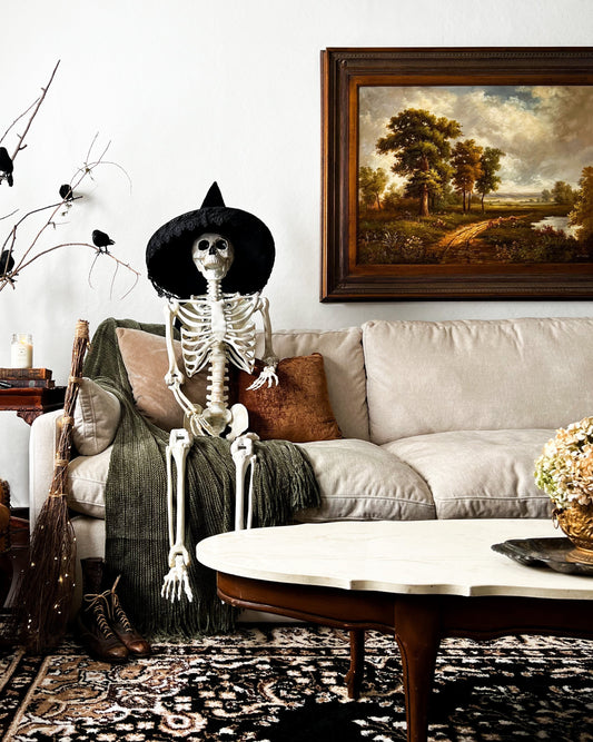 Halloween decorated living room with skeleton on white sofa, perfect spooky party setup for wickedly fun bash.