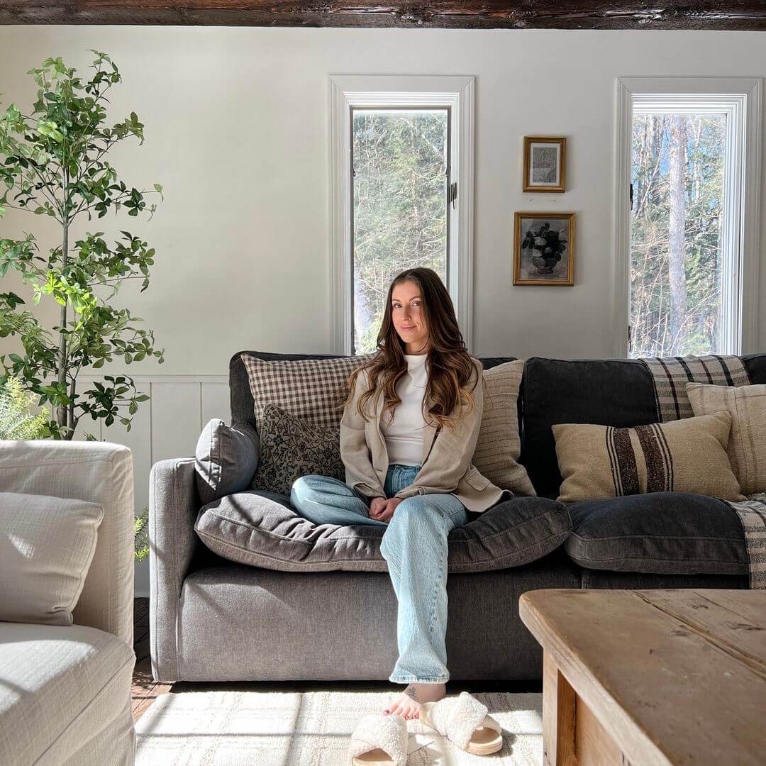 A woman sits cross-legged on a cozy sofa