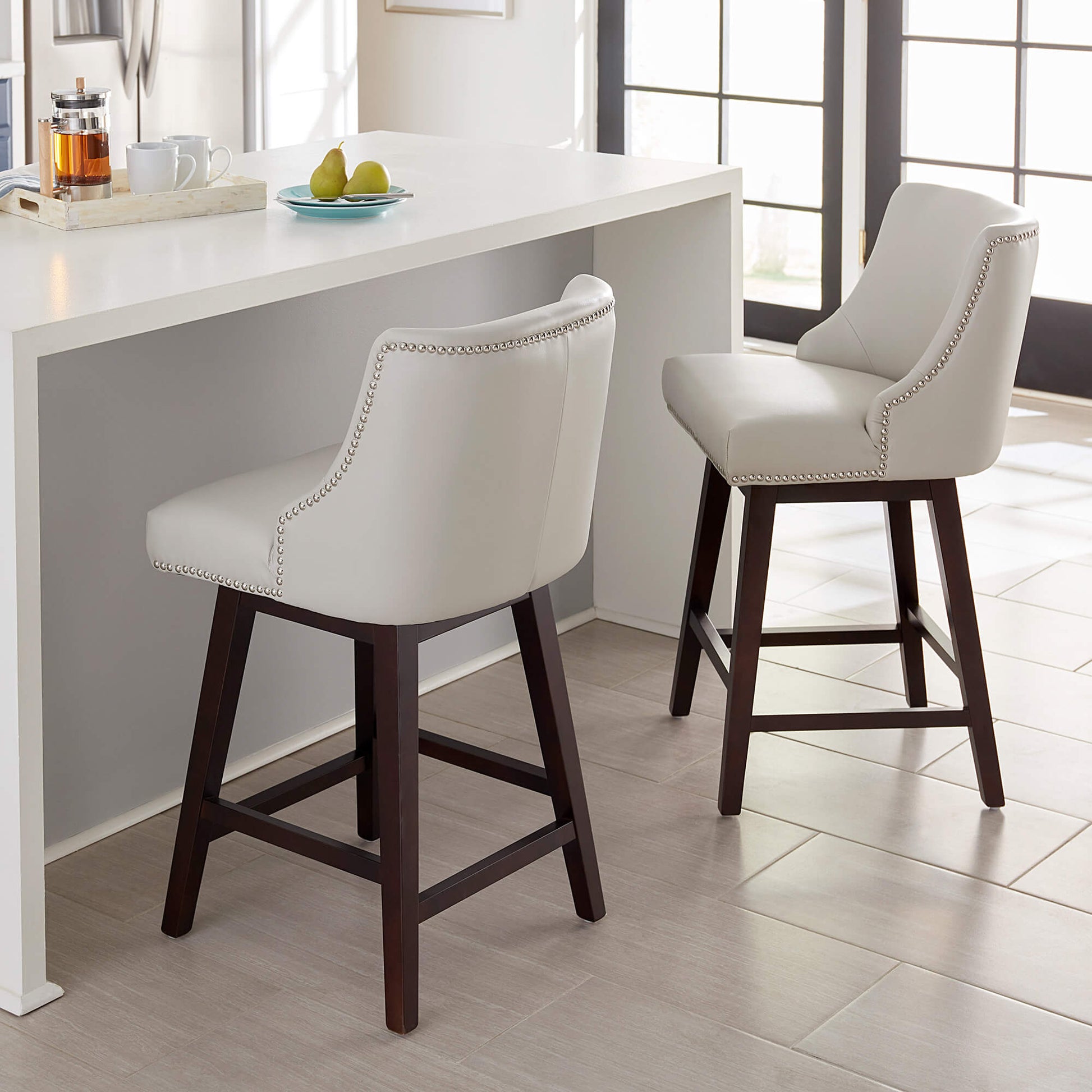 Asher swivel bar stools in white with silver nailhead trim at contemporary kitchen island - CHITA Living