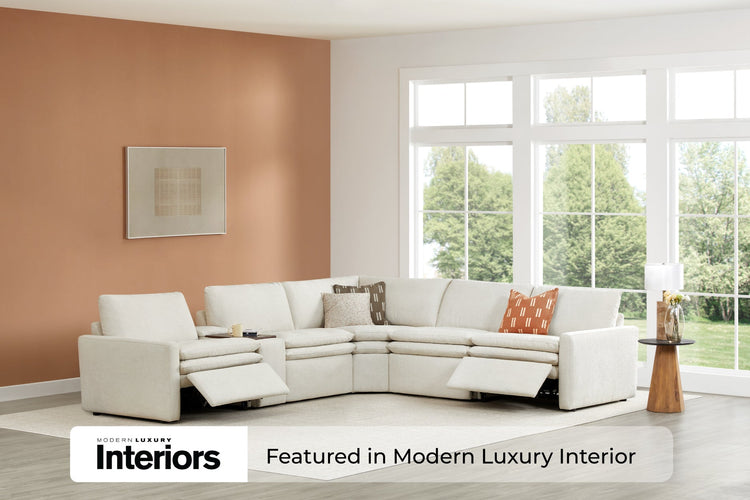 A beige sectional sofa with recliners in a room with large windows