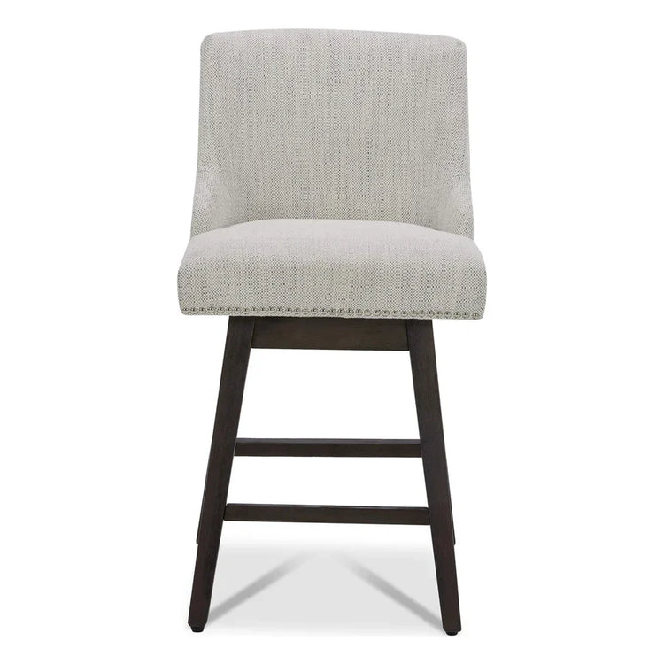 A beige upholstered counter stool with nailhead trim and dark wooden legs
