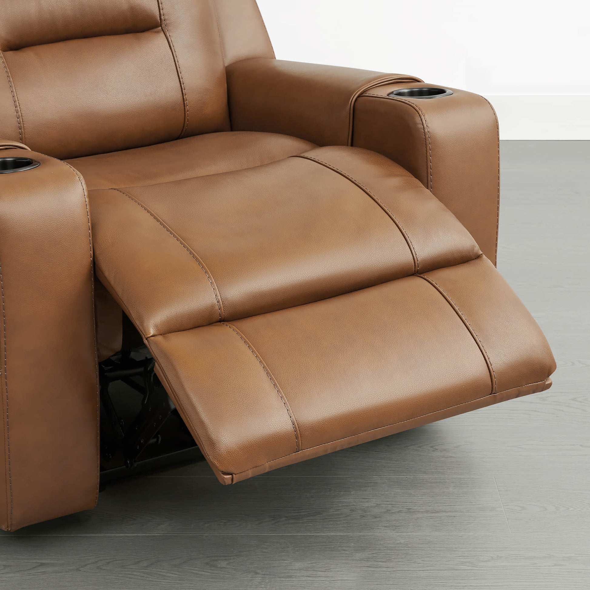 A tan leather recliner with the footrest extended and cup holders in both armrests.