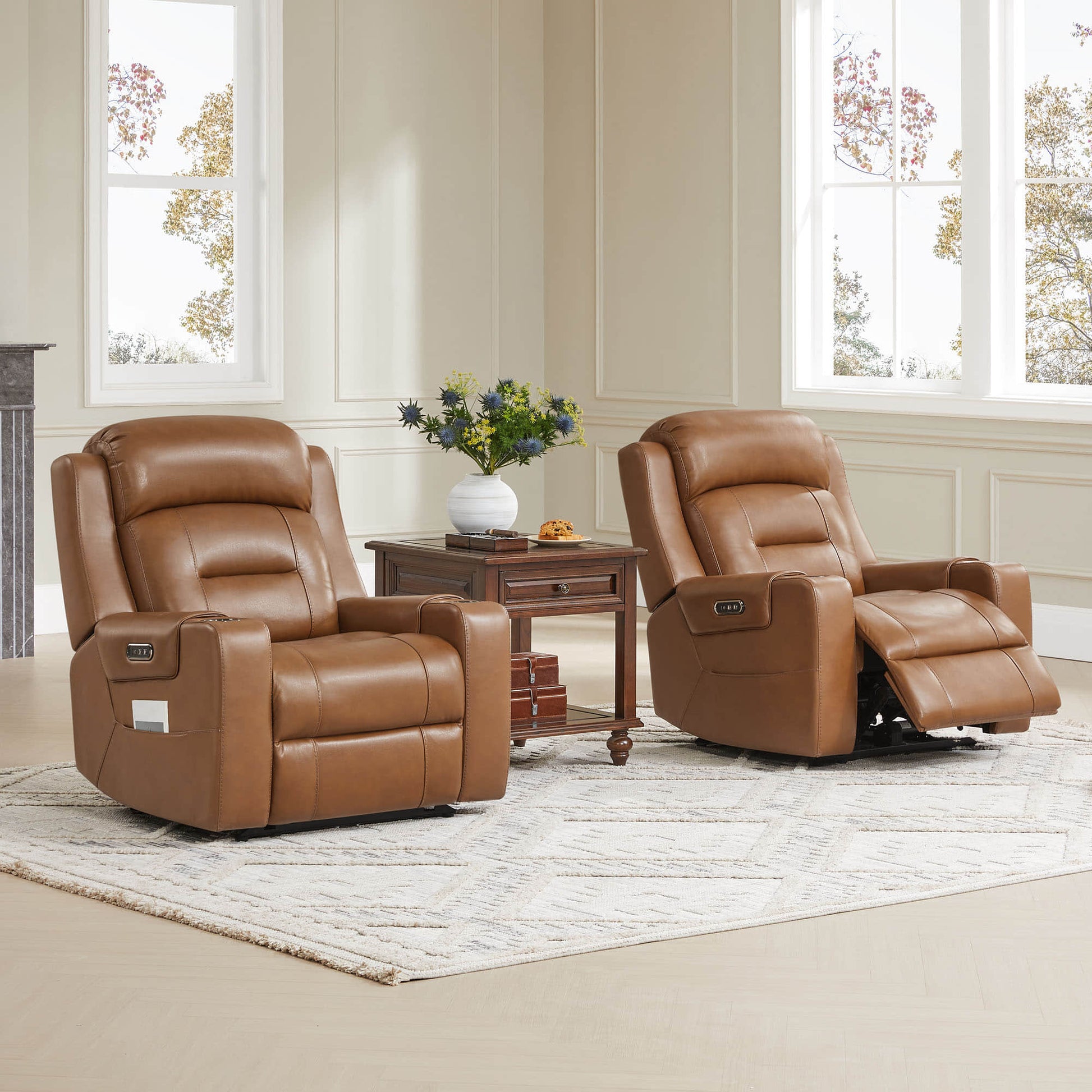 Two tan leather recliners with one partially reclined, next to a wooden side table in a bright room.