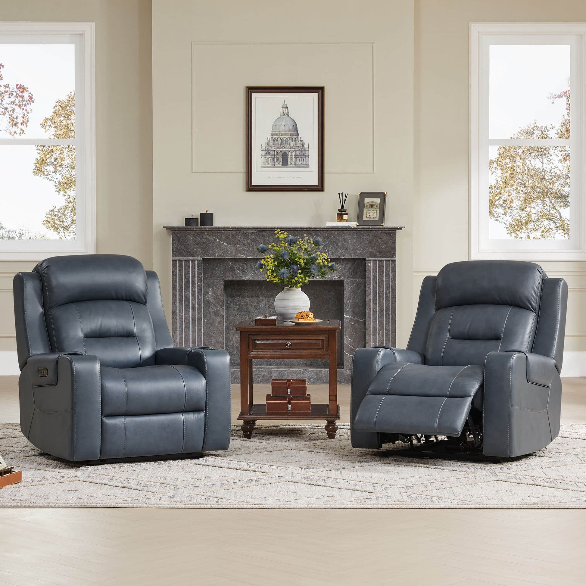 Two dark blue leather recliners with power headrests in a living room with a fireplace and side table.