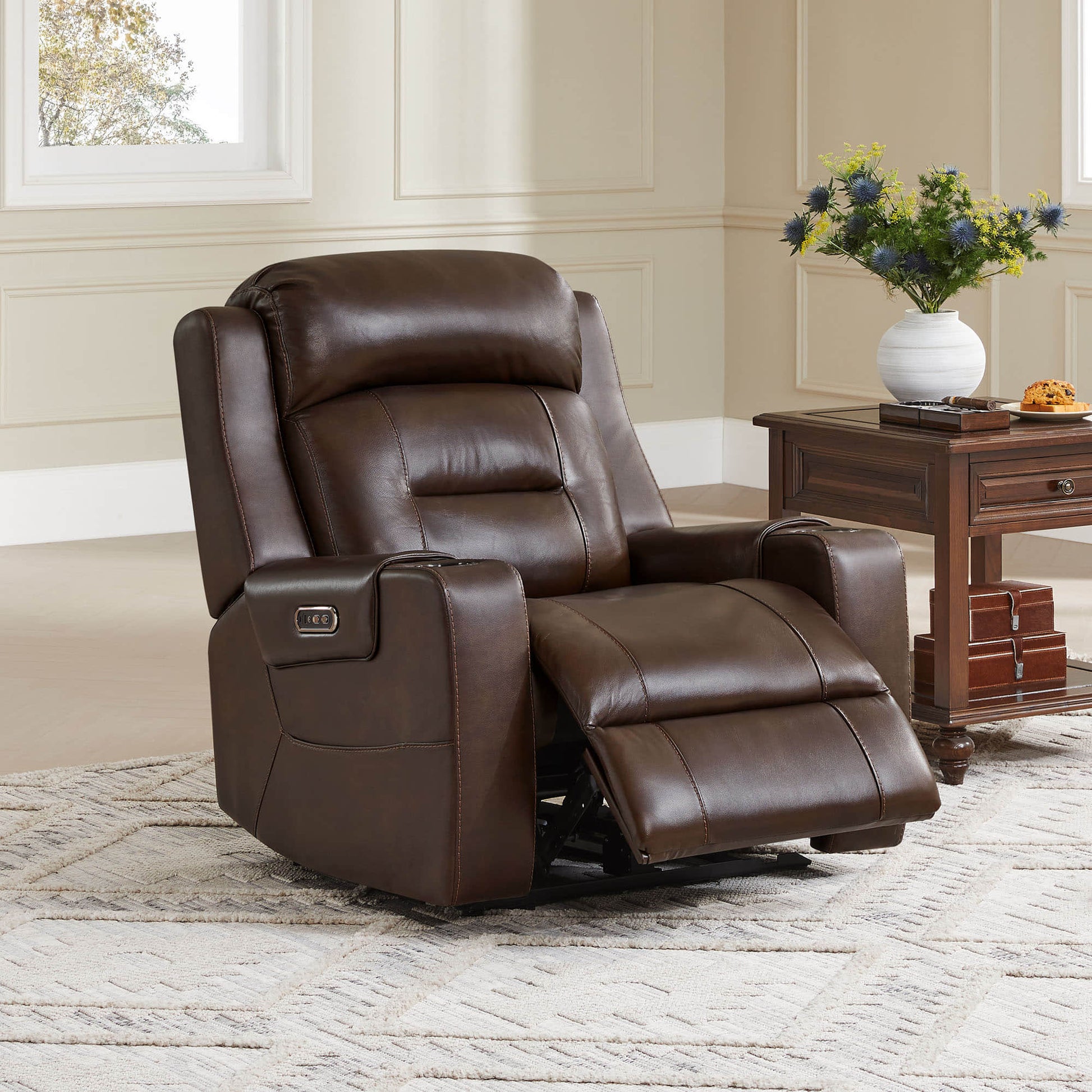 A brown leather recliner with cup holders, next to a wooden side table in a cozy living room setting.