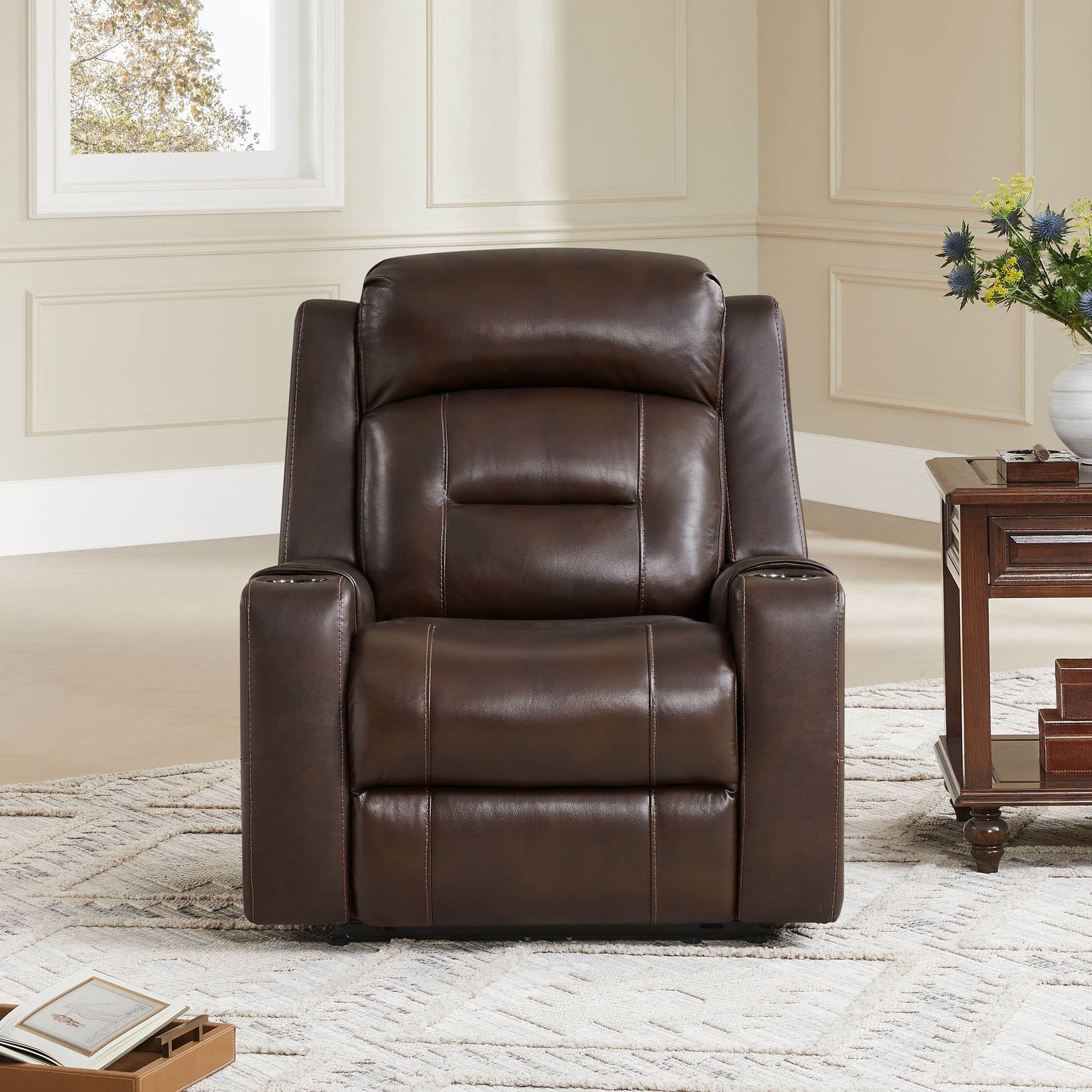 A brown leather recliner with cup holders, next to a wooden side table in a cozy living room setting.