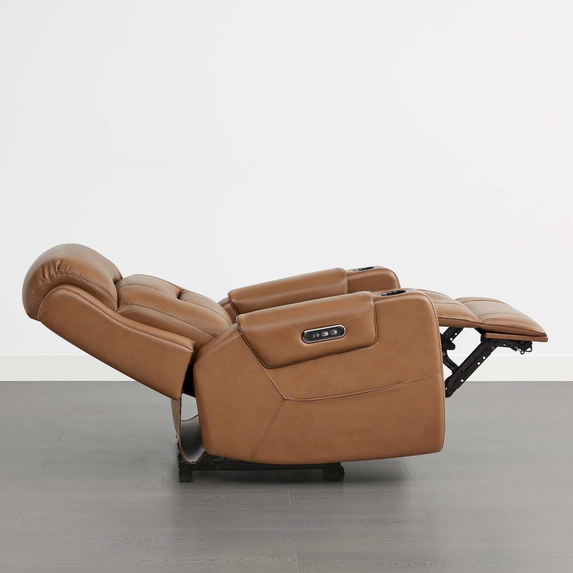 A tan leather recliner fully reclined, featuring a power headrest and control panel on the armrest.
