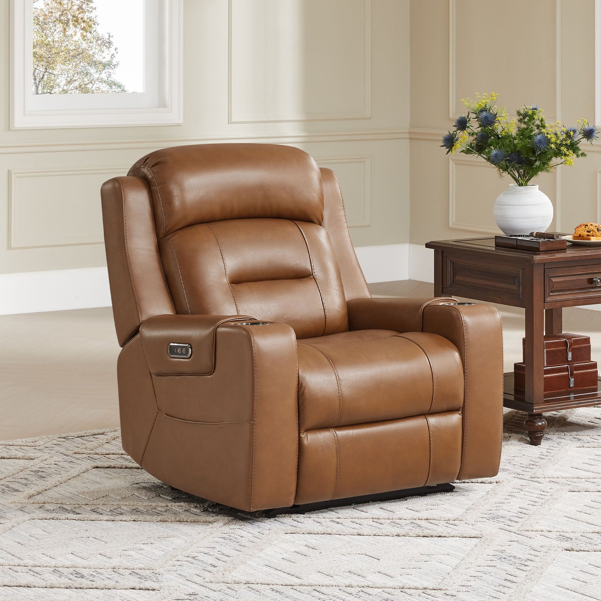 A tan leather recliner with cup holders, positioned next to a wooden side table in a cozy living room.