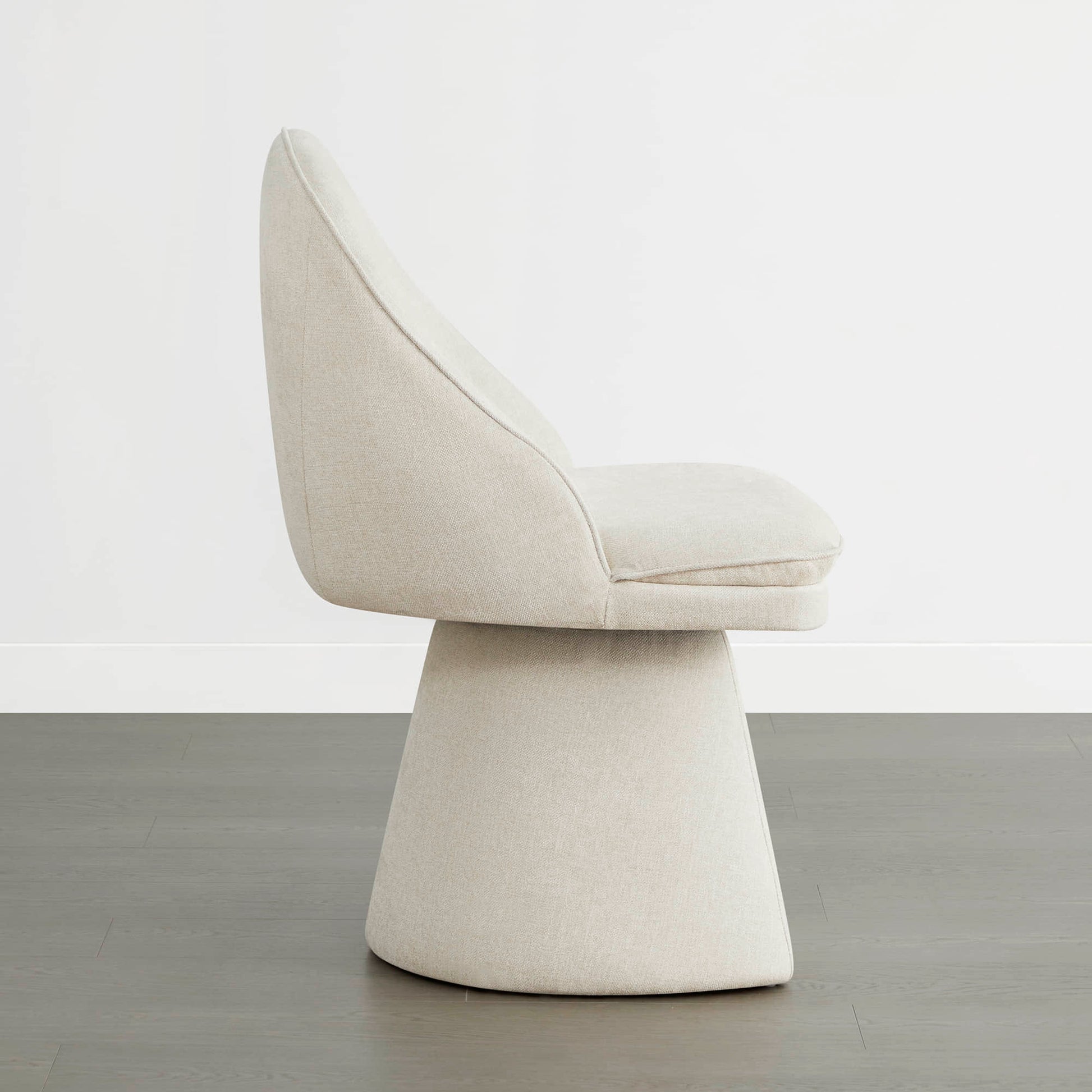 Side view of a cream swivel chair with a modern design and cushioned seat.