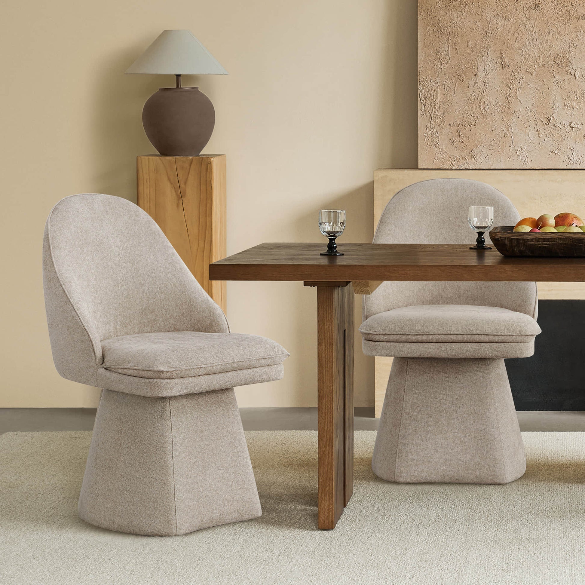 Modern dining setup with beige swivel chairs and a wooden table, warm and elegant.