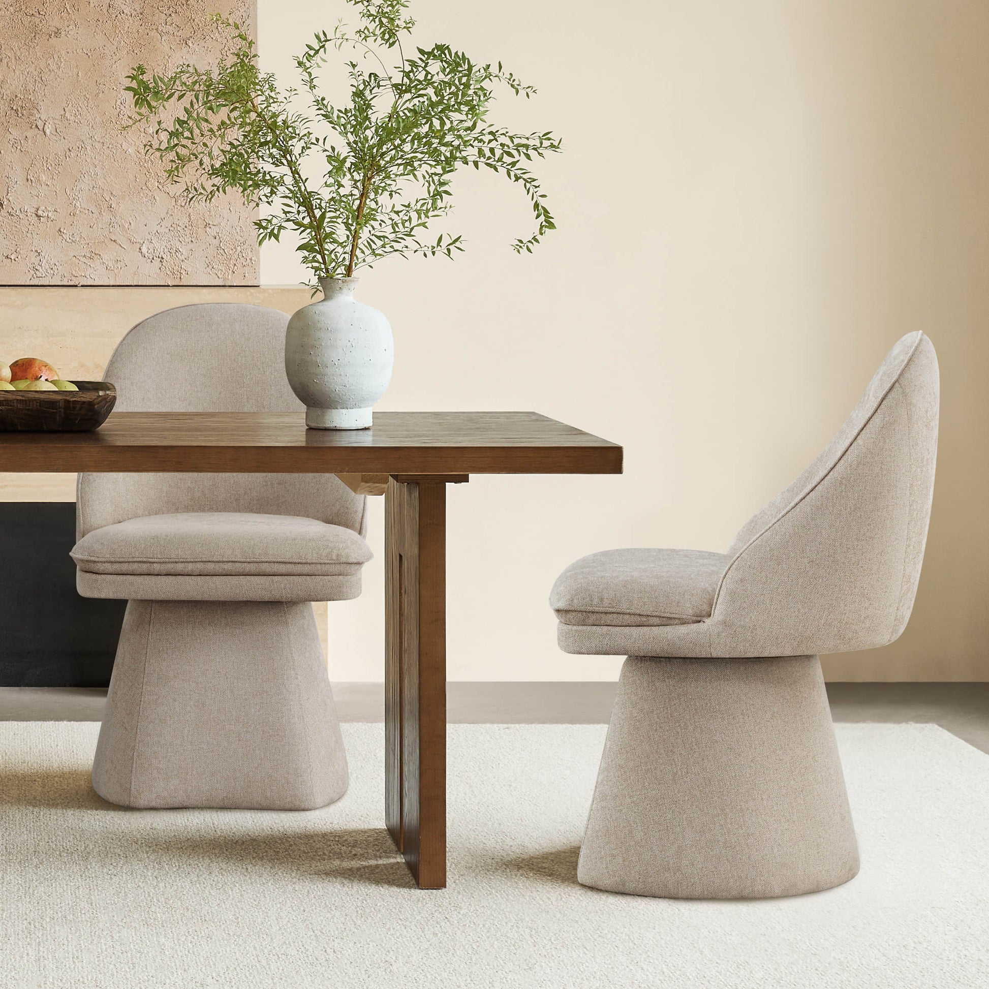 Modern dining area featuring beige swivel chairs and a wooden table, accented with greenery.