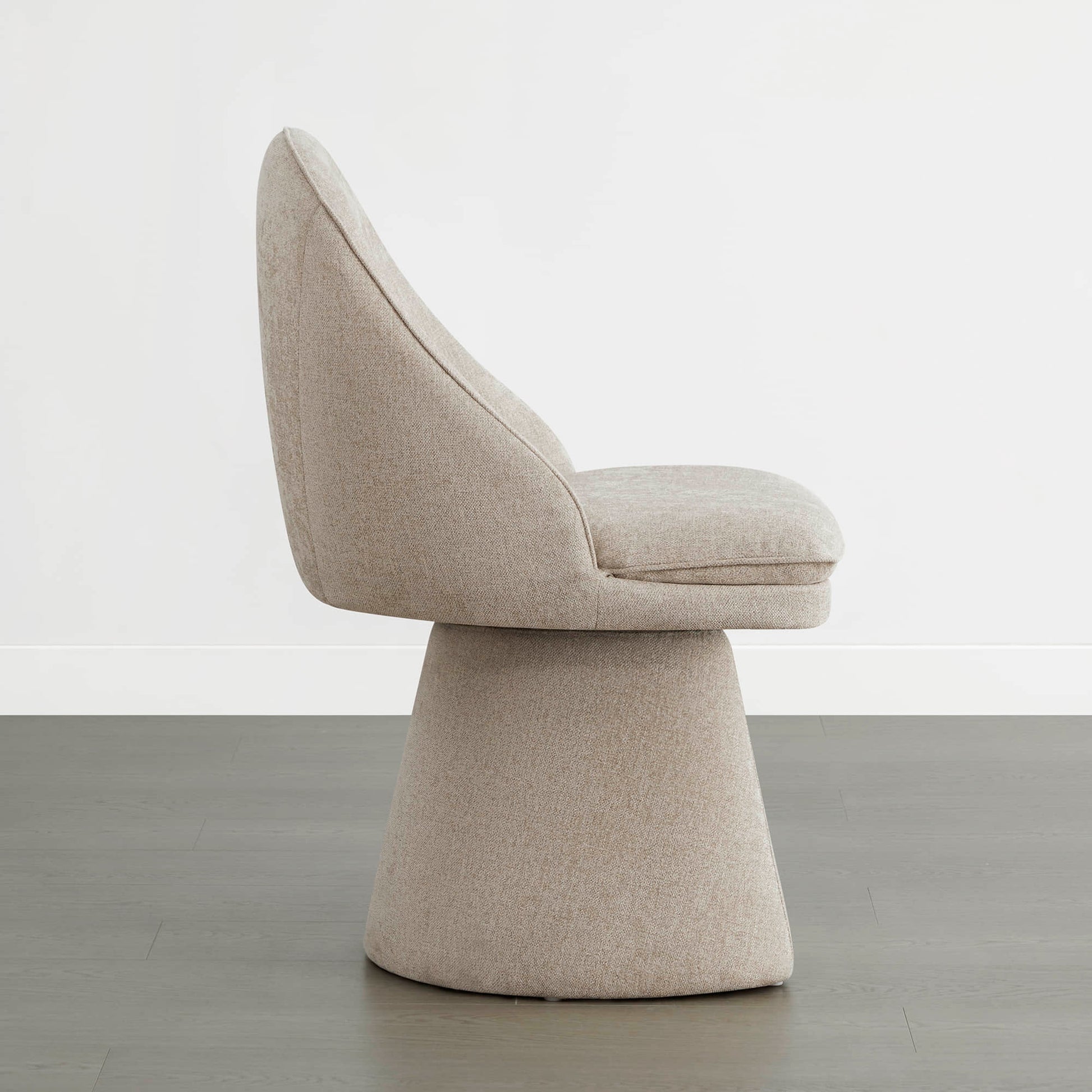 Side view of a modern swivel dining chair with a beige fabric finish.