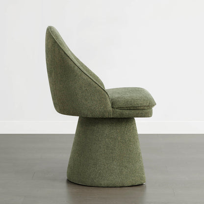 A green swivel chair viewed from the side, placed on a wooden floor against a white wall.