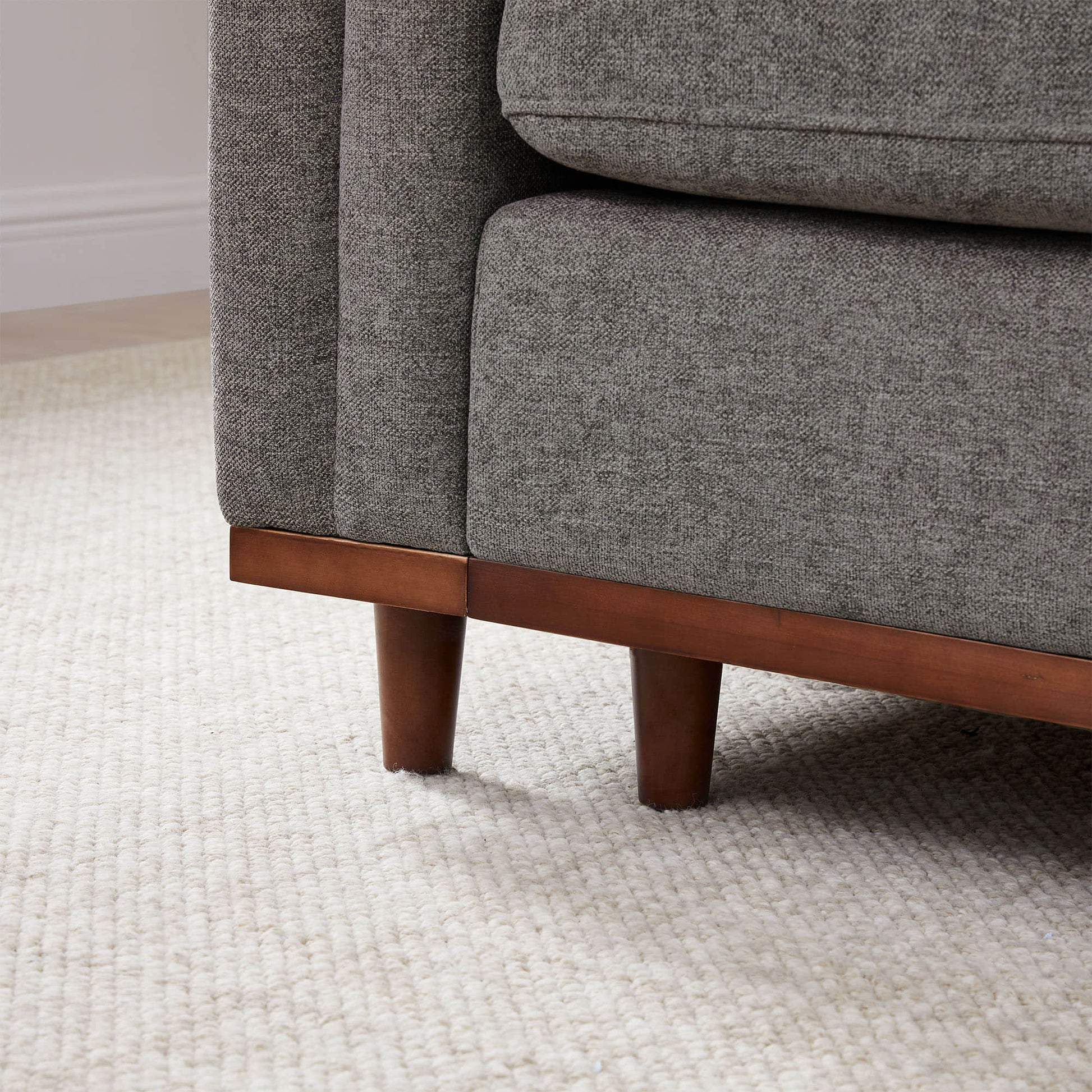 Close-up of Liam Sectional Sofa leg in dark wood with textured gray upholstery - CHITA Living