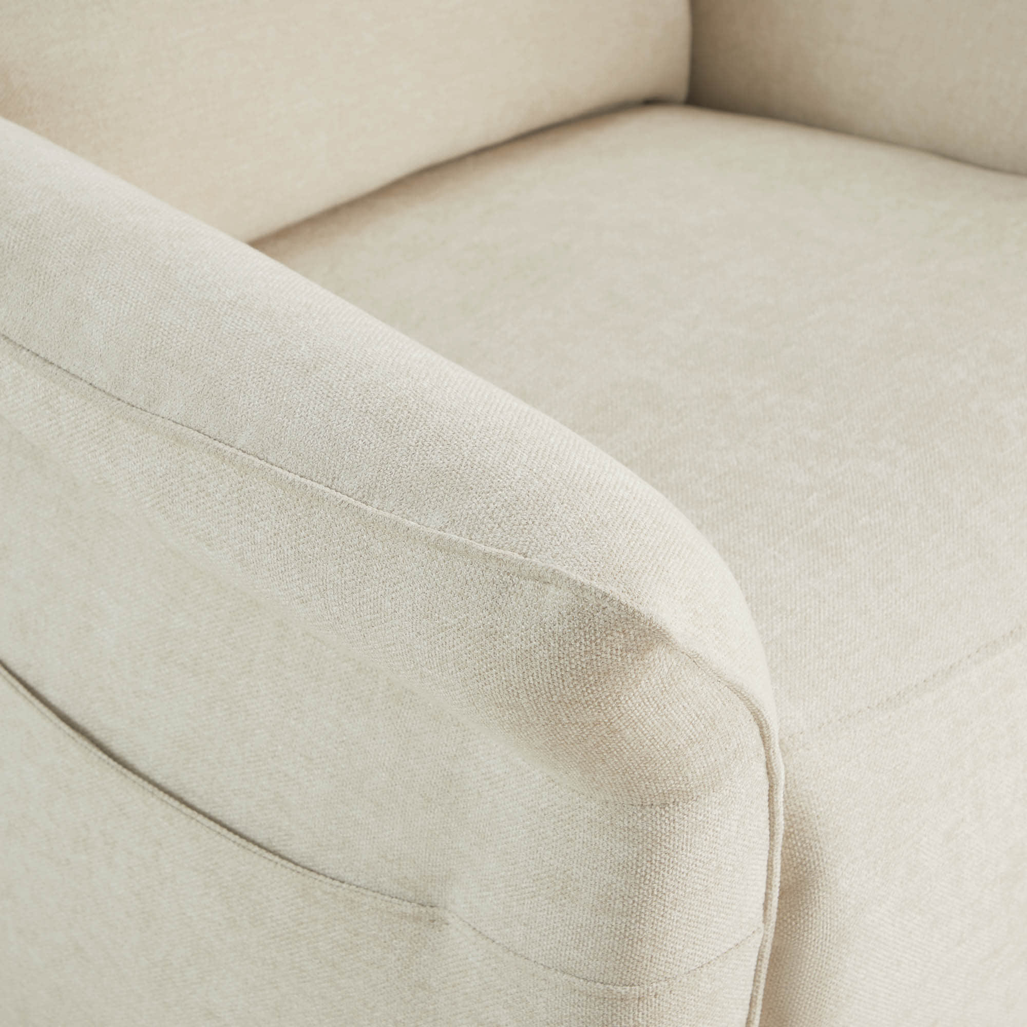 Detail of cream power recliner's armrest showing quality upholstery stitching.