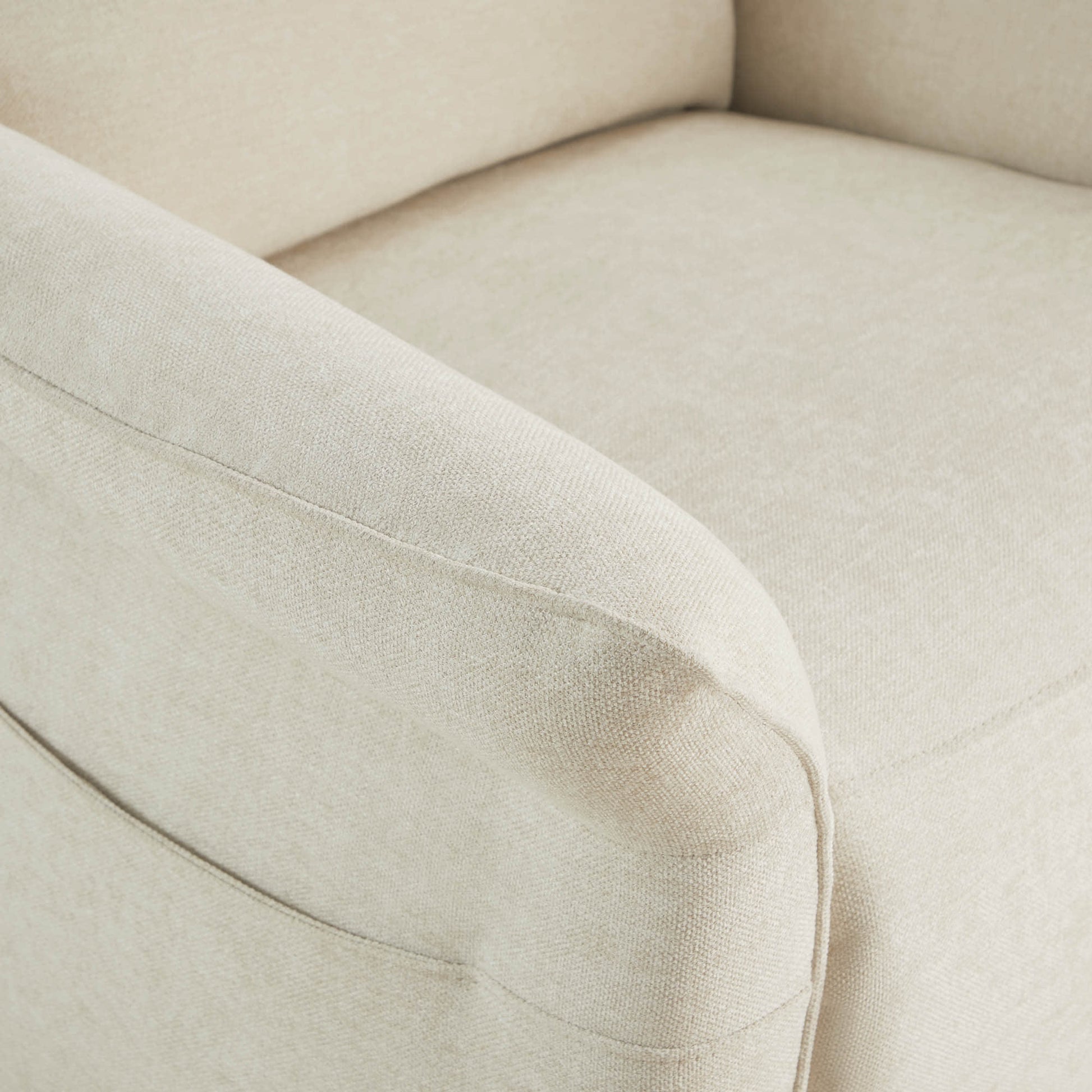 Detail of cream power recliner's armrest showing quality upholstery stitching.