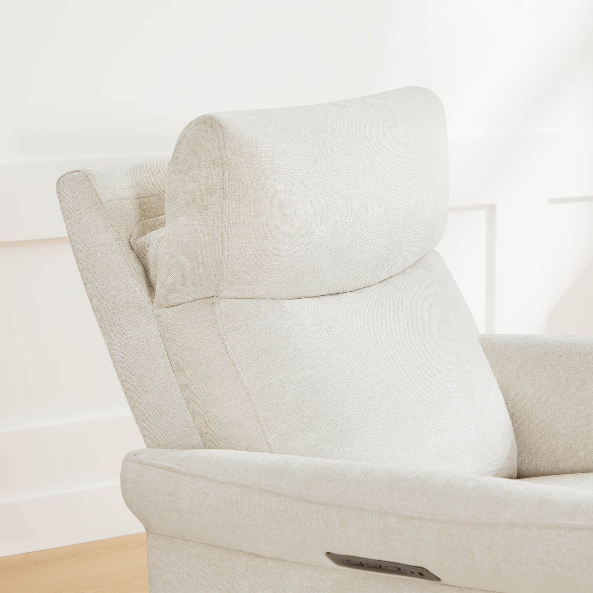 Close-up of cream swivel recliner showcasing plush headrest and armrest design.