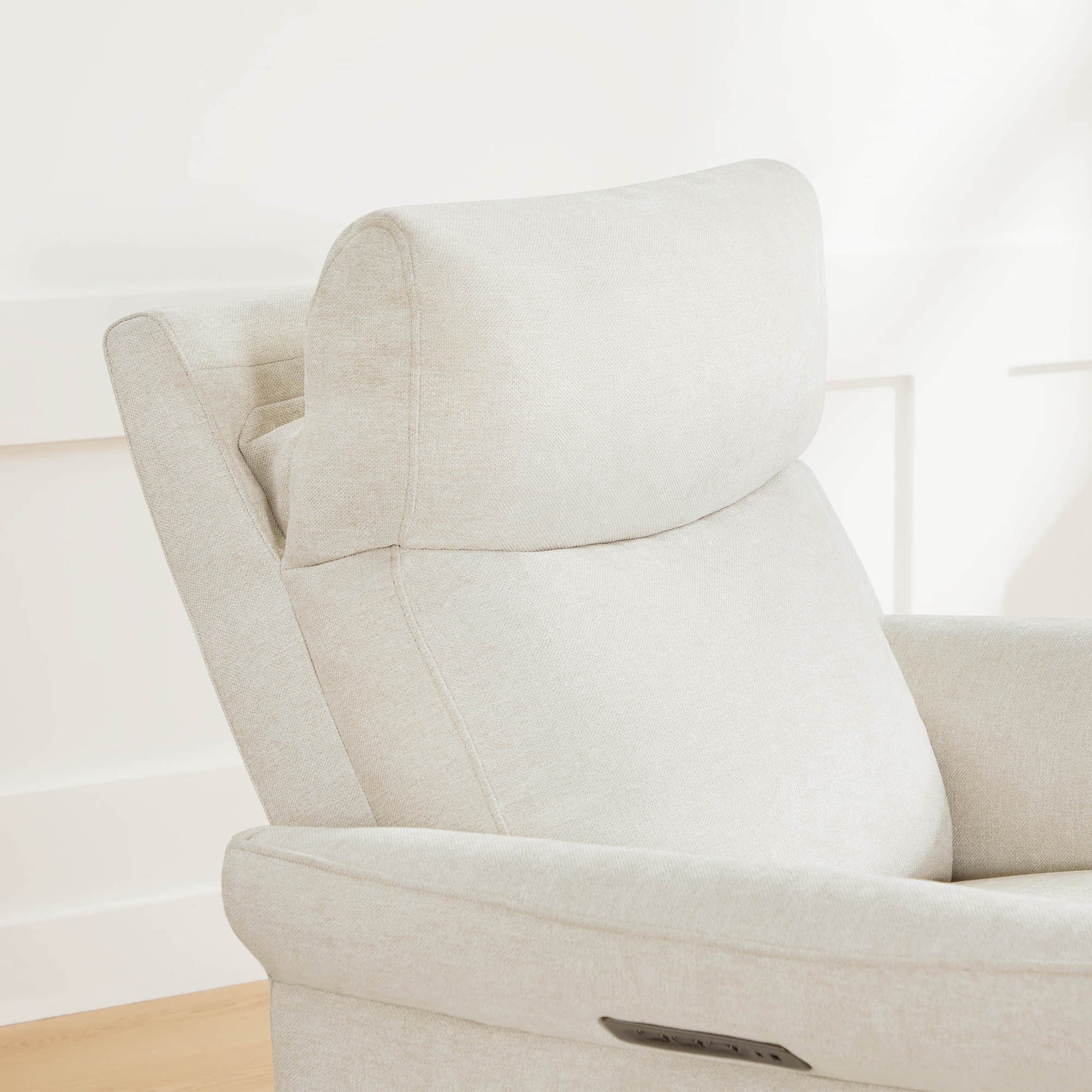 Close-up of cream swivel recliner showcasing plush headrest and armrest design.