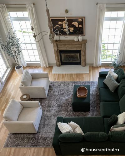 A spacious living room with a dark green sofa, white armchairs