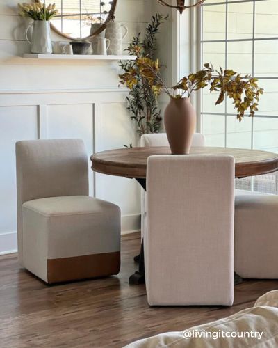A cozy dining area with a round wooden table, beige upholstered chairs