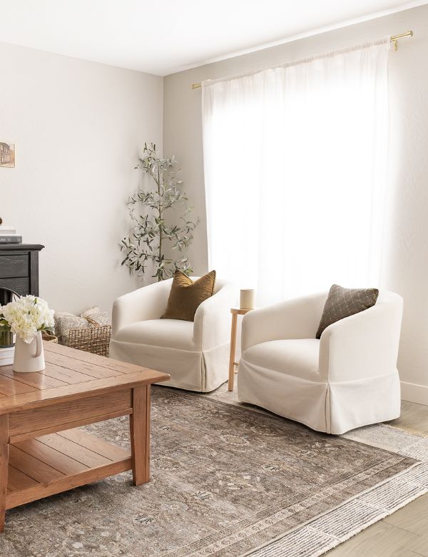 A cozy living room with two cream armchairs, a wooden coffee table