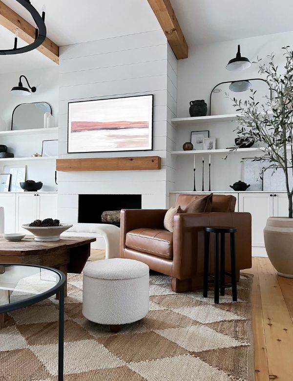 A modern living room with a brown leather sofa, white ottoman