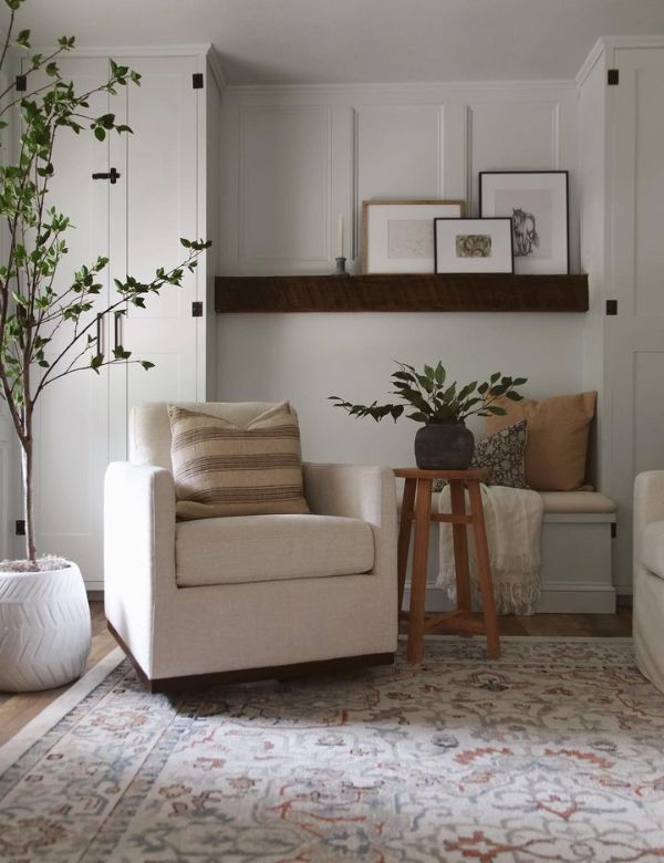 A cozy corner with a cream armchair, a wooden stool