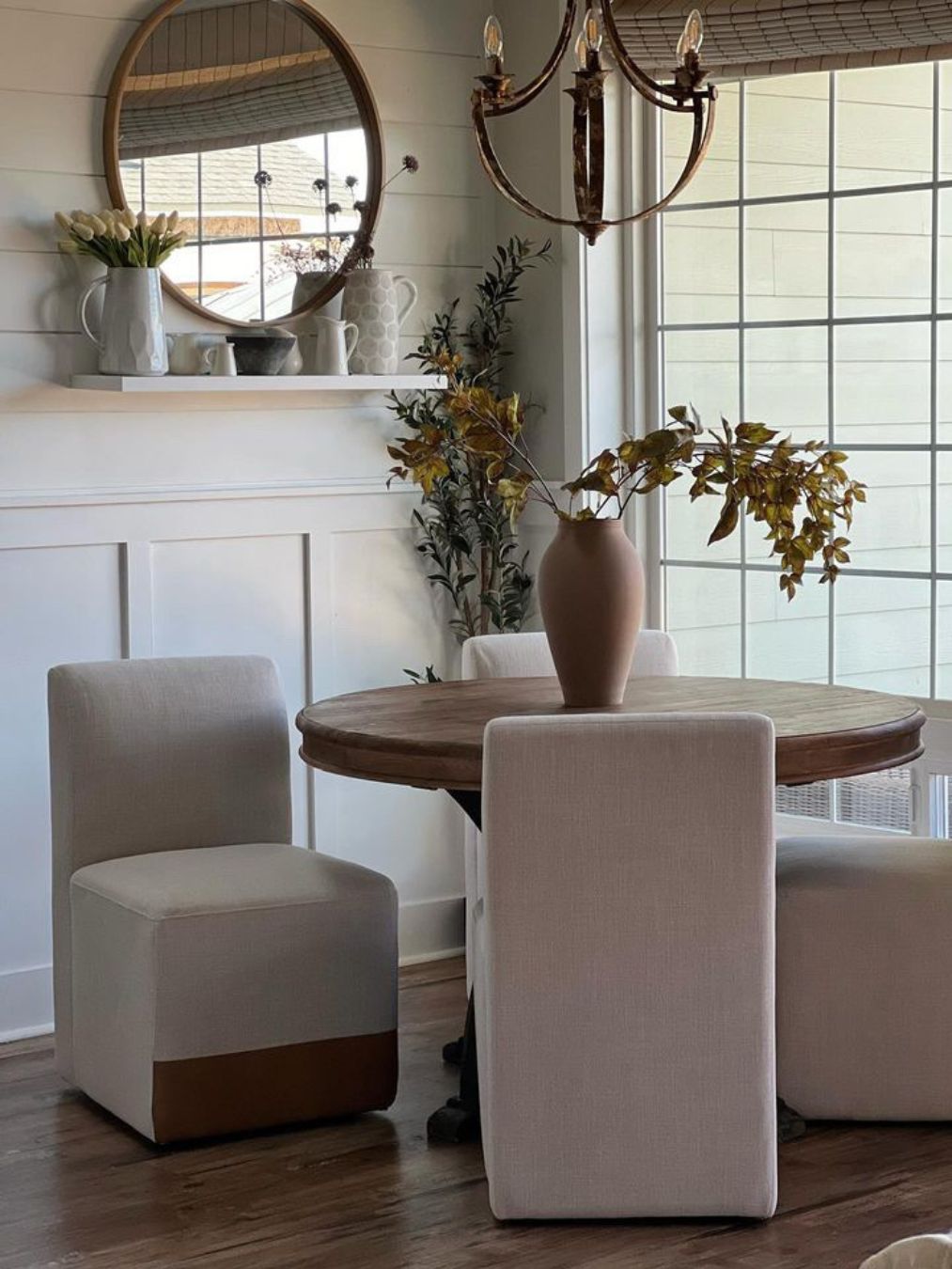 A round wooden dining table with beige upholstered chairs