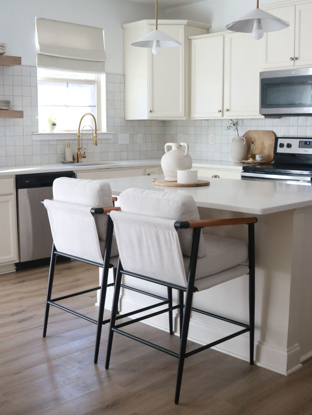 A modern kitchen with white cabinets, a subway tile backsplash, and black bar stools