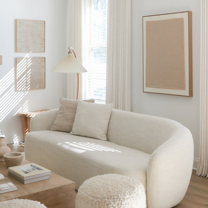 A modern, curved beige sofa with cushions