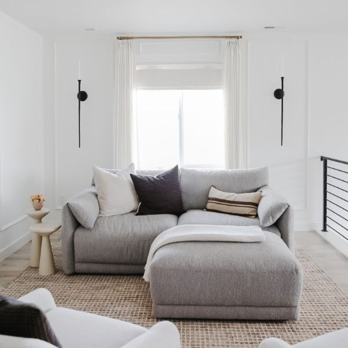 A cozy gray sectional sofa with various cushions and a matching ottoman