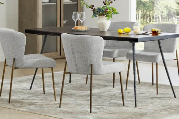 A modern dining set with a dark wooden table and gray upholstered chairs with gold legs.